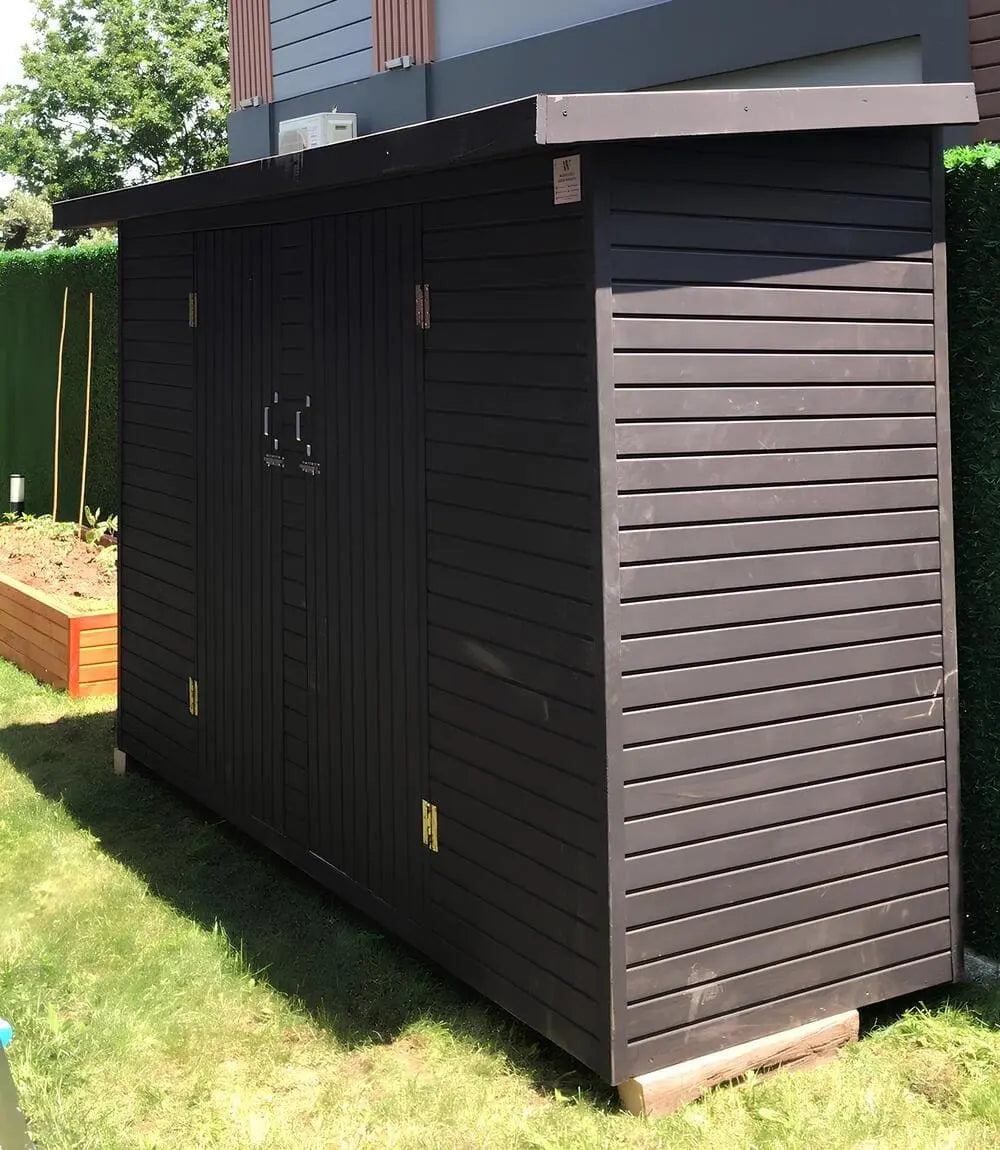 Ev bahçesinde kullanılan ahşap ardiye kulübesi, antrasit dış cephe kaplaması ve çelik takviyeli kapılar